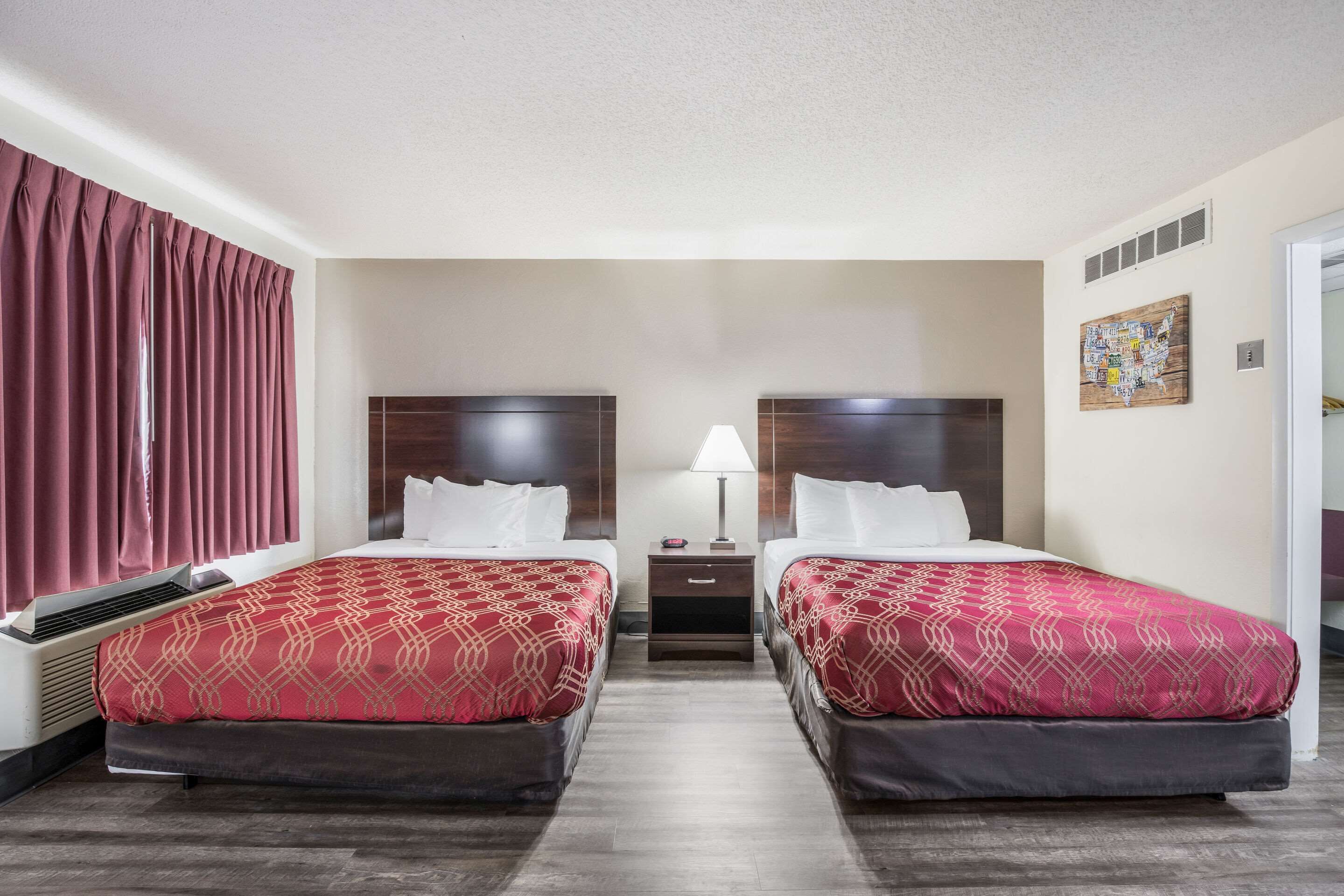 Une chambre d’hôtel avec deux lits, une table de chevet, une lampe et une carte géographique accrochée au mur.