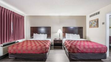 Une chambre d’hôtel avec deux lits, une table de chevet, une lampe et une carte géographique accrochée au mur.