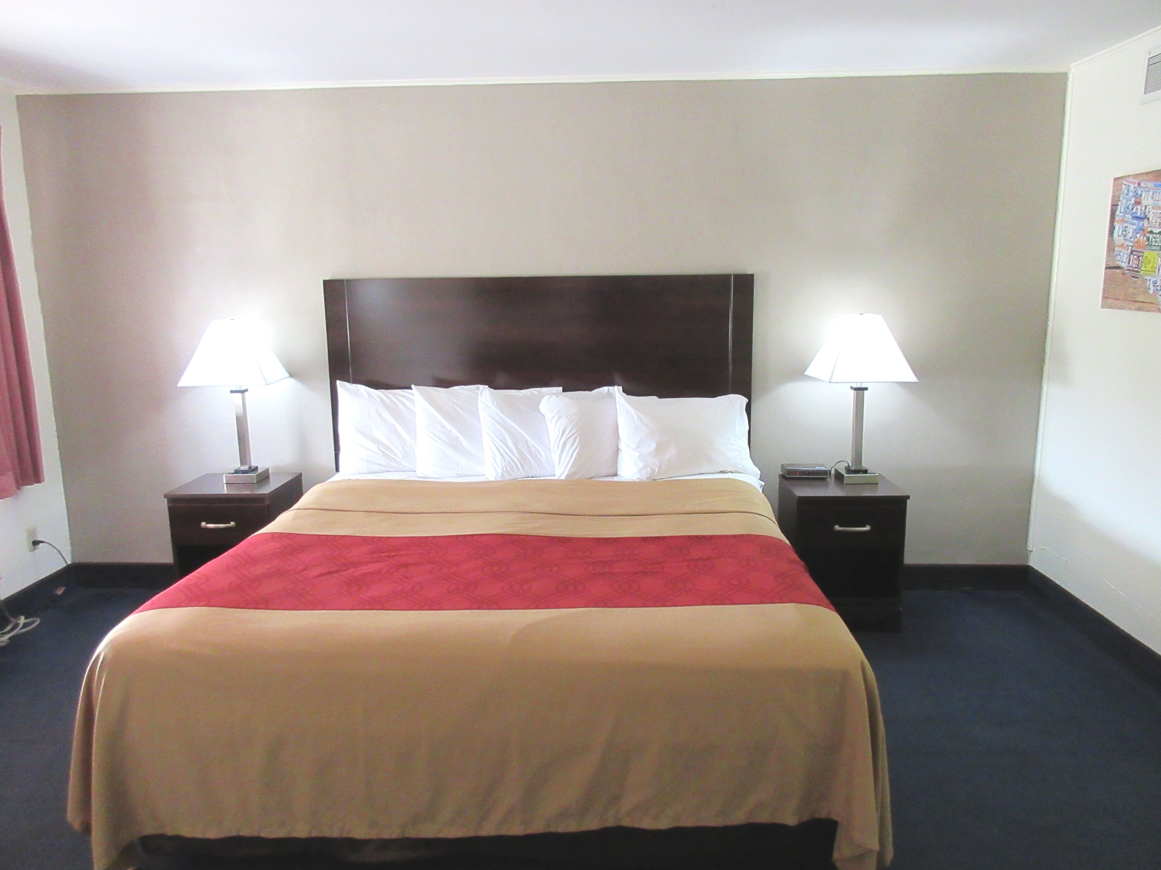A hotel room with a large bed, two bedside tables, and two lamps.