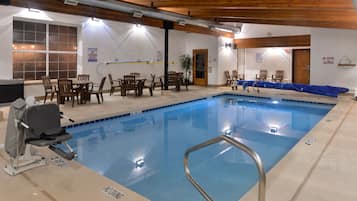 Piscina interior con socorrista, techo de madera y zona de estar.