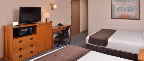 A hotel room with two beds, a desk with a computer, a television, and a microwave.