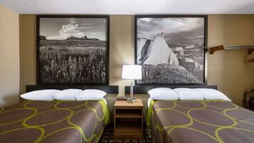 Camera d'albergo con due letti, un comodino con una lampada e due grandi fotografie di paesaggi appese al muro.