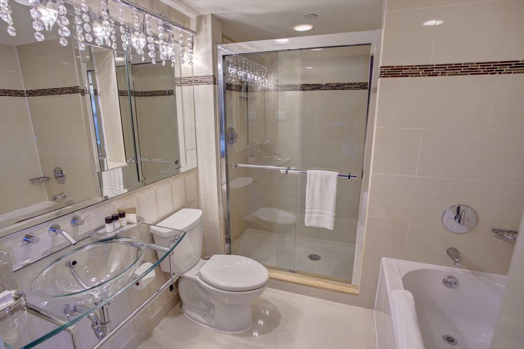 A modern bathroom with a glass-enclosed shower, a glass sink, and a bathtub.