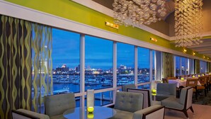 A modern dining area with large windows, a view of the marina, and a unique chandelier. - Golden Nugget (Atlantic City)