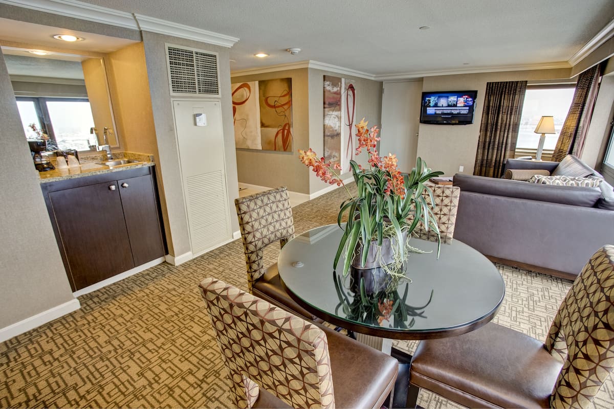 A hotel room with a dining area, a sofa, and a TV.