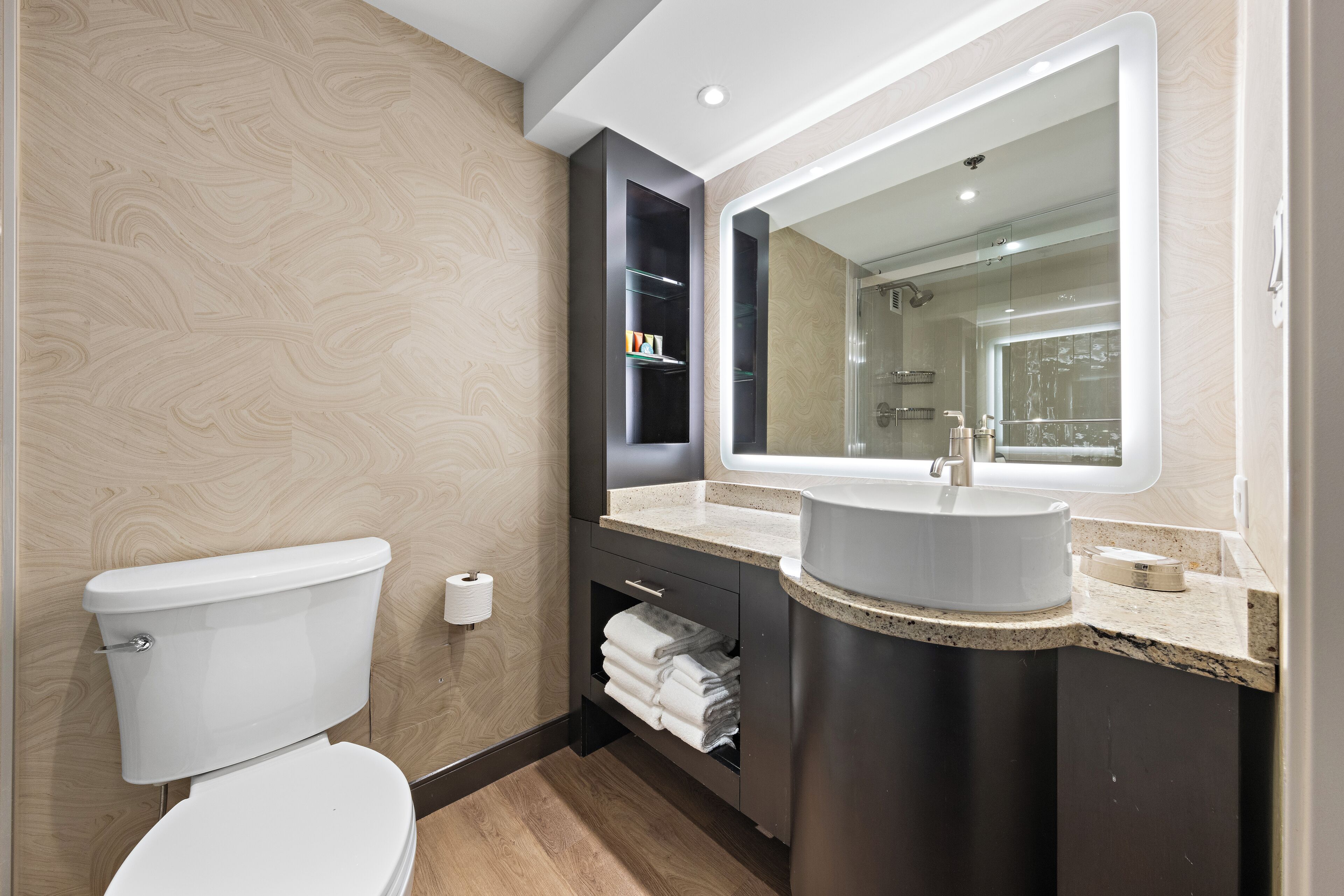 Et moderne badeværelse med toilet, vaskemøbel og et stort spejl.