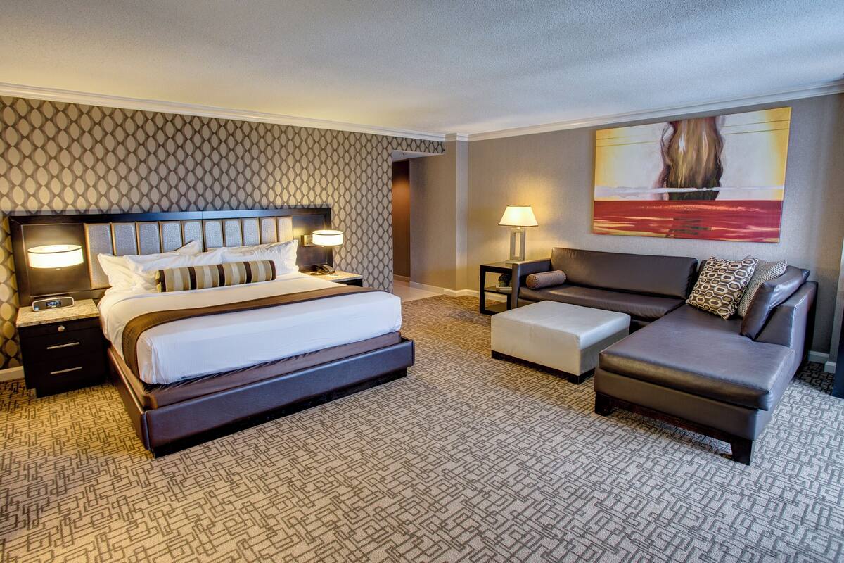 A hotel room with a large bed, a sofa, a small table, and a lamp.