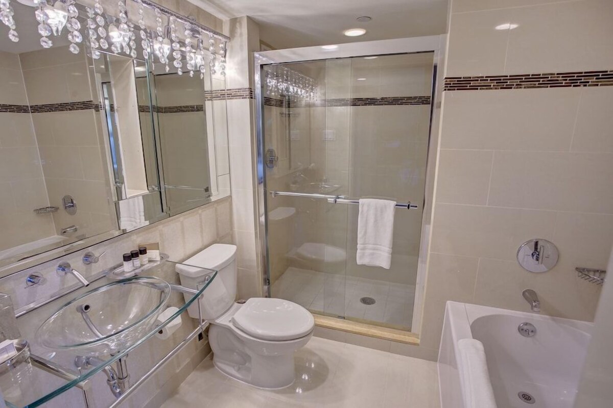 Ein modernes Badezimmer mit einer Duschkabine, einem Waschbecken aus Glas und einer weißen Toilette.