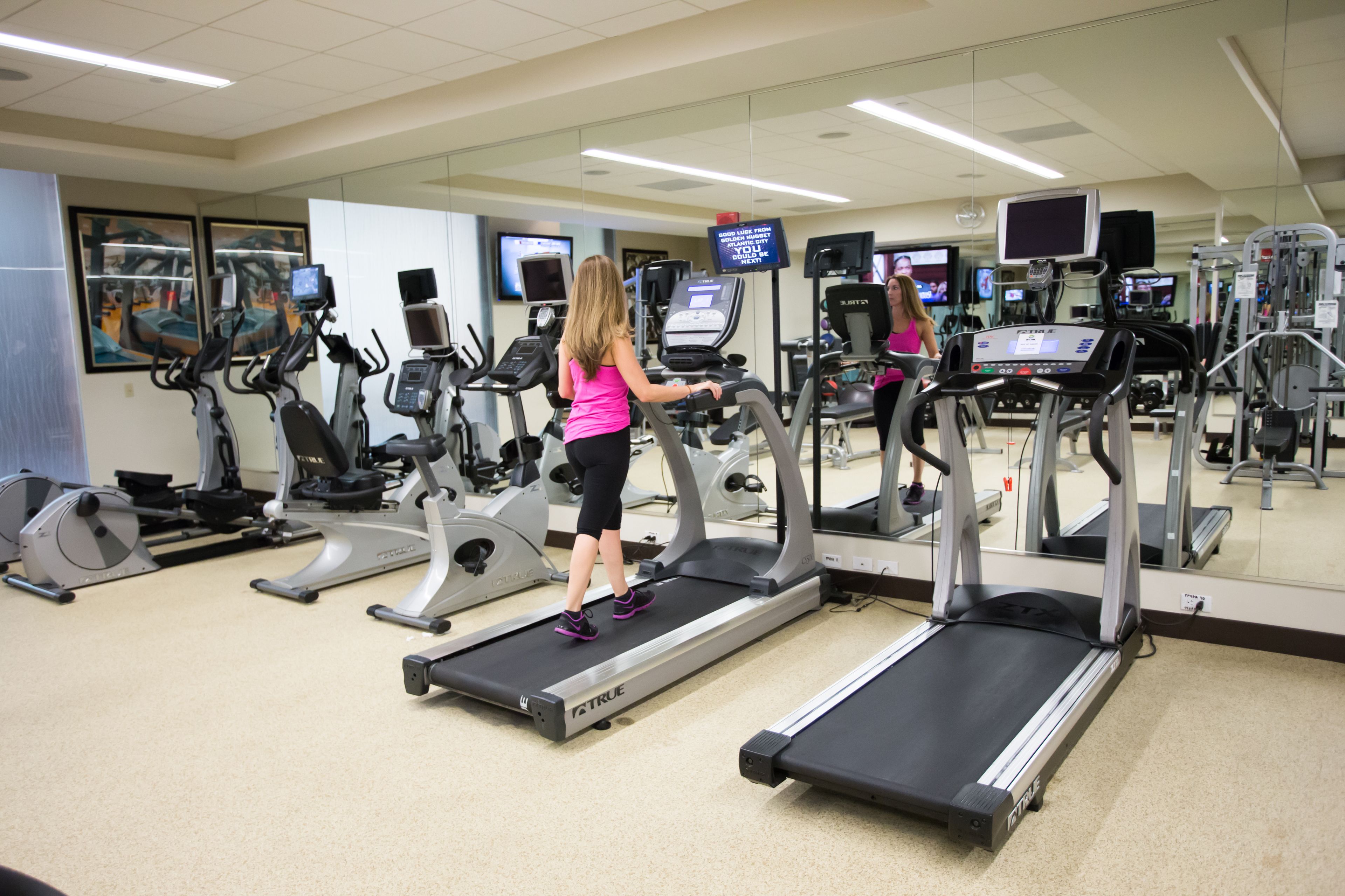 Un gimnasio con cintas de correr, bicicletas estáticas y equipo de ejercicio.