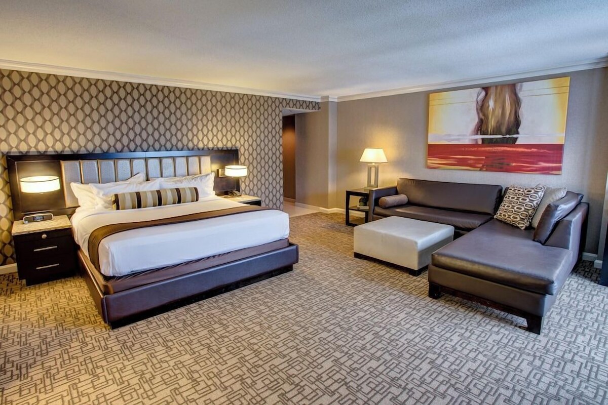 Ein Hotelzimmer mit einem großen Bett, einer Couch, einem kleinen Tisch und einem Gemälde an der Wand.