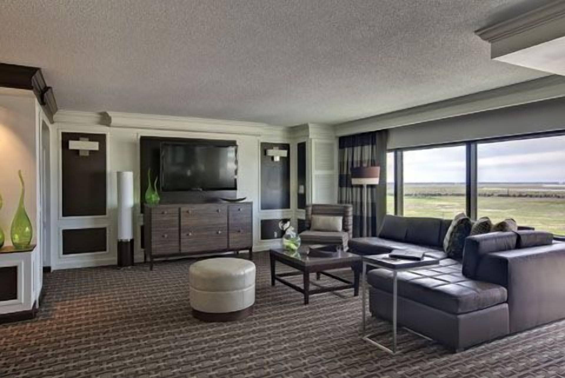 A modern living room with a flat-screen TV, a sofa, a coffee table, and a view of the outdoors.