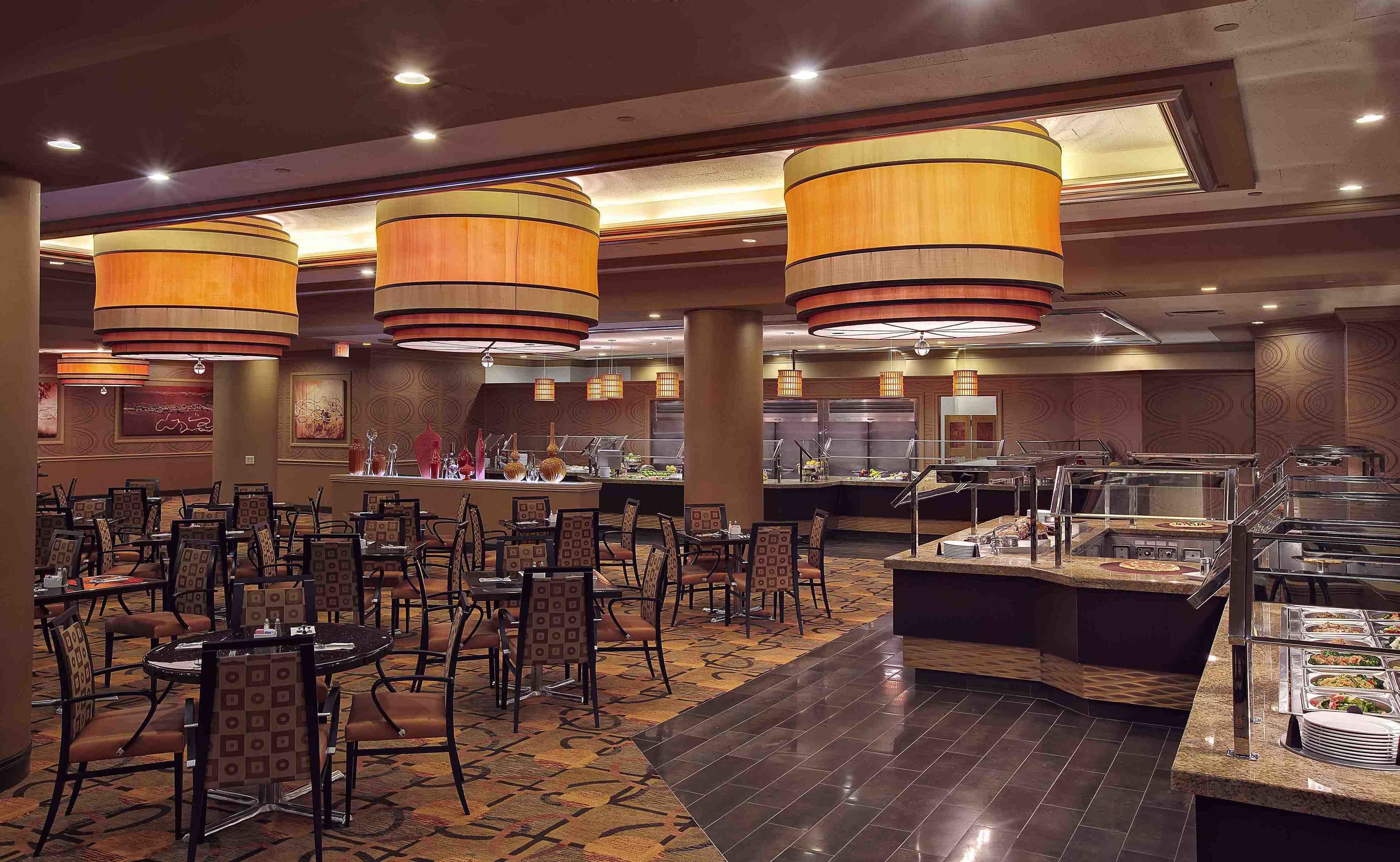 Un espace buffet comprenant plusieurs stands de nourriture, des tables rondes et des chaises.