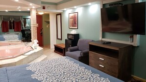 A hotel room with a large bed, a sitting area with a chair, a television, a microwave, and a bathtub. - Days Inn by Wyndham Nanuet / Spring Valley (Nanuet)