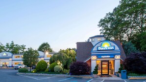 A Days Inn hotel with a registration area, parking lot, and surrounding greenery. - Days Inn by Wyndham Nanuet / Spring Valley (Nanuet)