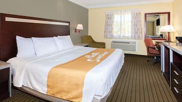 A hotel room with a large bed, a desk, a chair, a mirror, and a window with curtains.