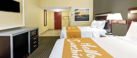 A hotel room with a bed, a desk, a television, and a painting on the wall.