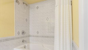 A bathroom with a white bathtub, a shower, and a yellow wall. - Days Inn by Wyndham Nanuet / Spring Valley (Nanuet)
