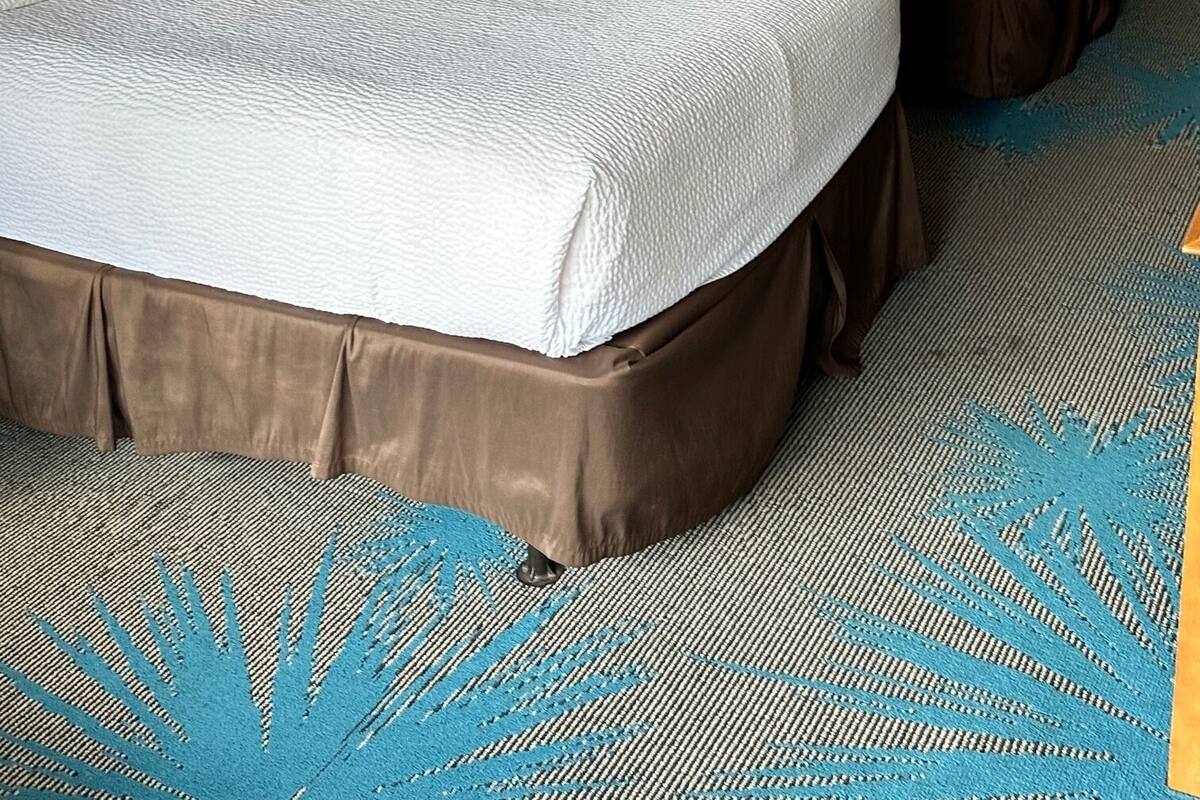 A hotel room with two beds, a nightstand, a lamp, and a painting on the wall.