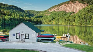 Une cabane avec un quai, des canoës et un lac.