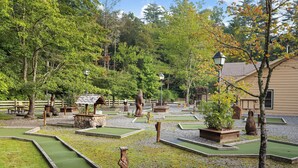 Un parcours de mini-golf doté de plusieurs zones d’entraînement au putting, entouré d’arbres et de structures en bois.