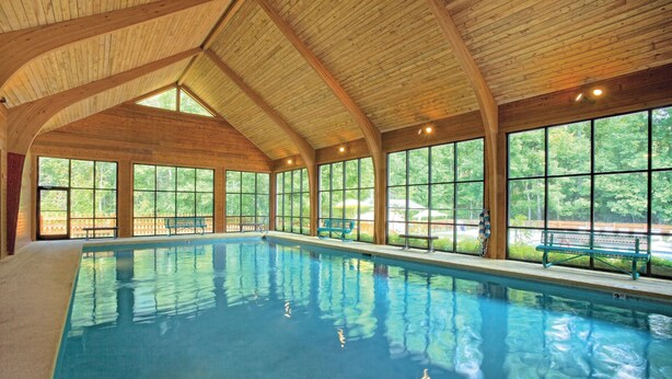 Une piscine intérieure avec des poutres en bois et de grandes fenêtres.