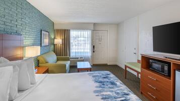 Una camera d'albergo con un letto, un divano, una TV, un forno a microonde e una scrivania.