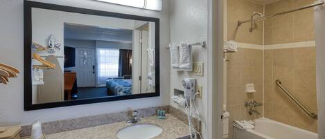 A bathroom with a sink, mirror, towel rack, and a shower with a grab bar.
