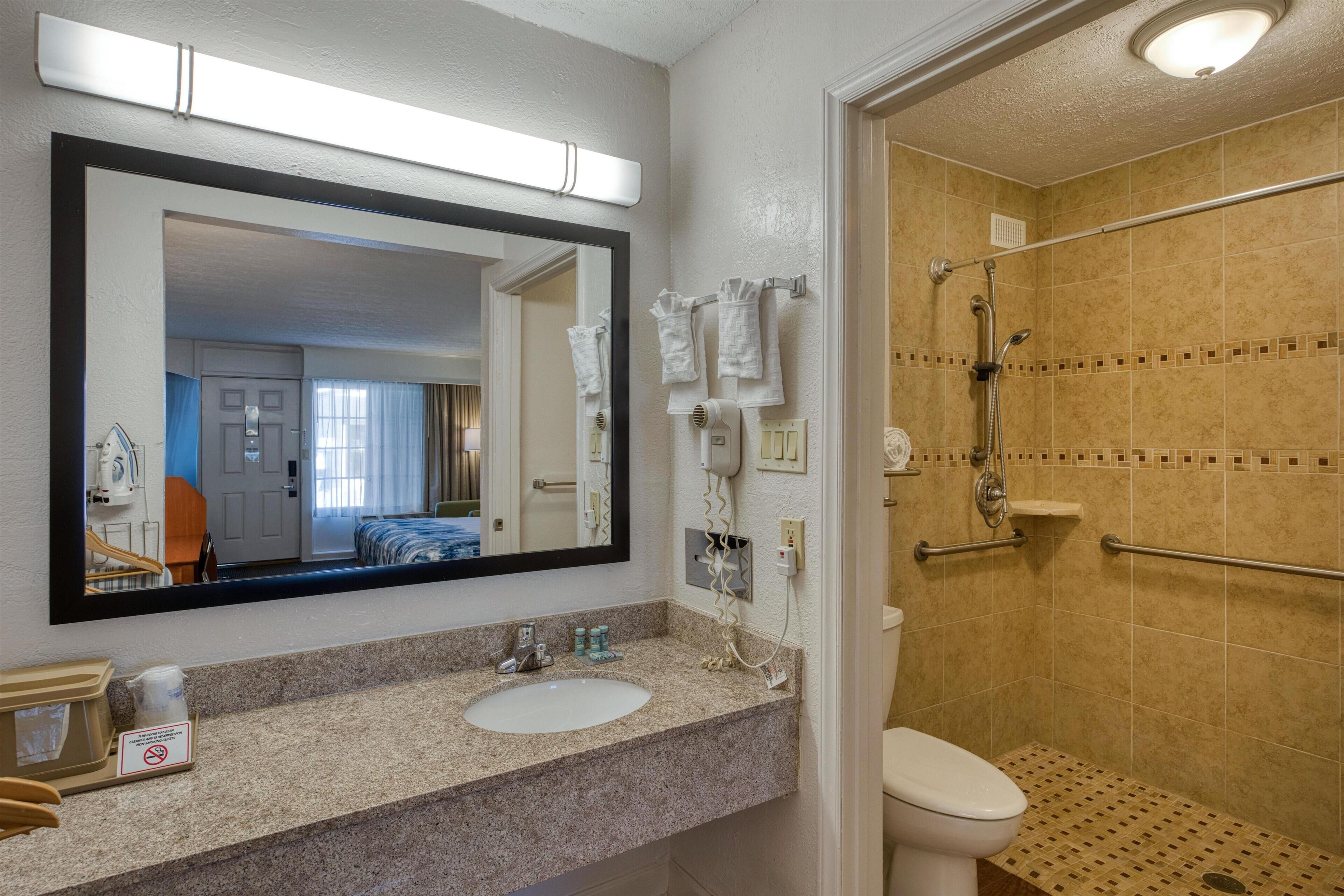Une salle de bain équipée d’un lavabo, d’un miroir, d’un porte-serviettes et d’une douche.