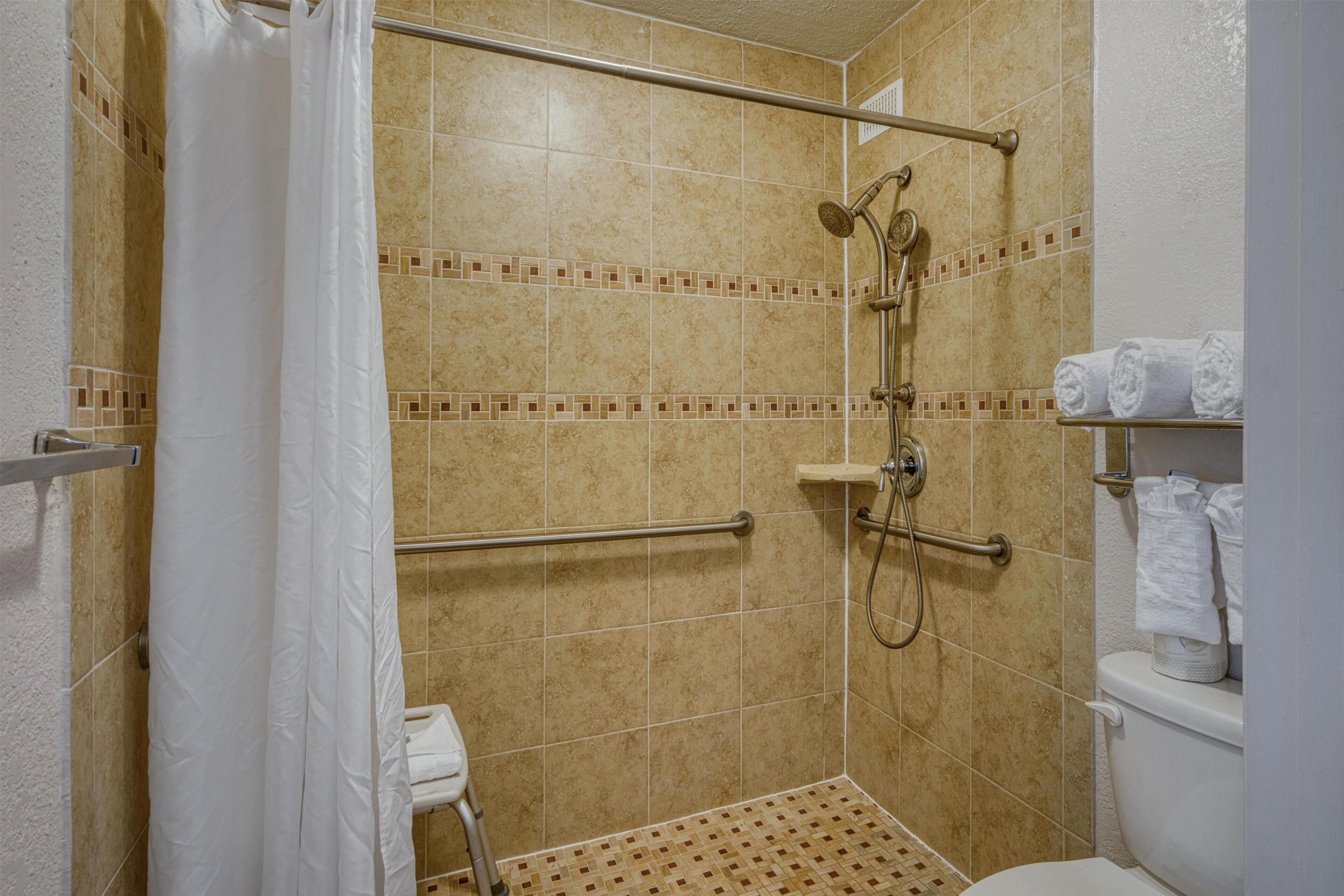 Um banheiro pequeno com azulejos, chuveiro, vaso sanitário e porta-toalhas.