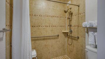 Um banheiro pequeno com azulejos, chuveiro, vaso sanitário e porta-toalhas.