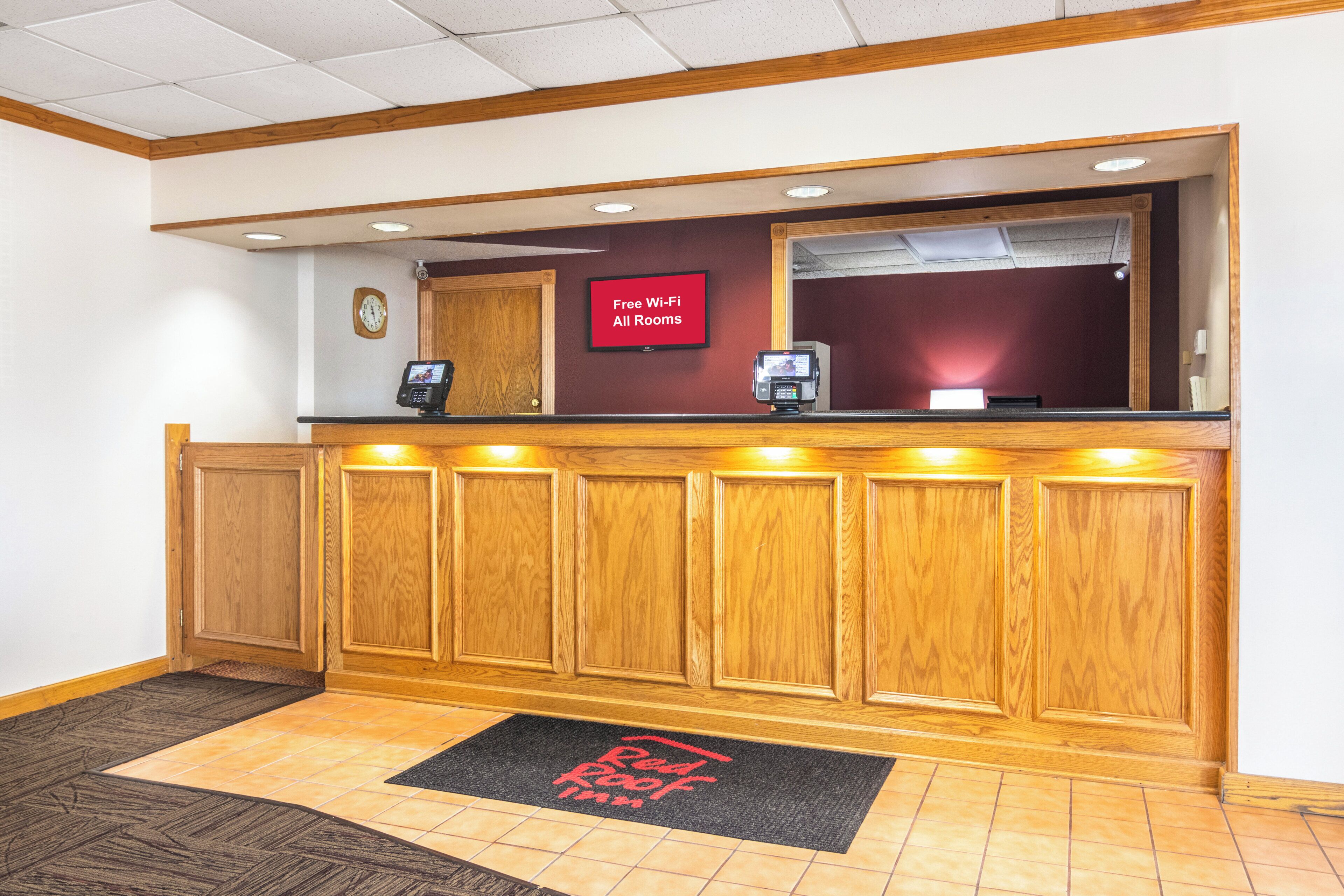 A reception desk with a clock, a digital display, and a sign indicating free Wi-Fi availability.