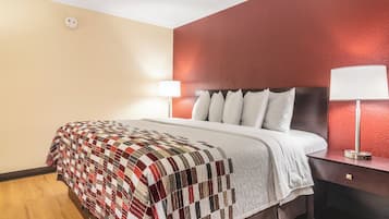 Ein Hotelzimmer mit einem Bett, einem Nachttisch, einer Lampe und einer Wand mit strukturierter Oberfläche.