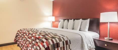 A hotel room with a bed, a nightstand, a lamp, and a wall with a textured finish.