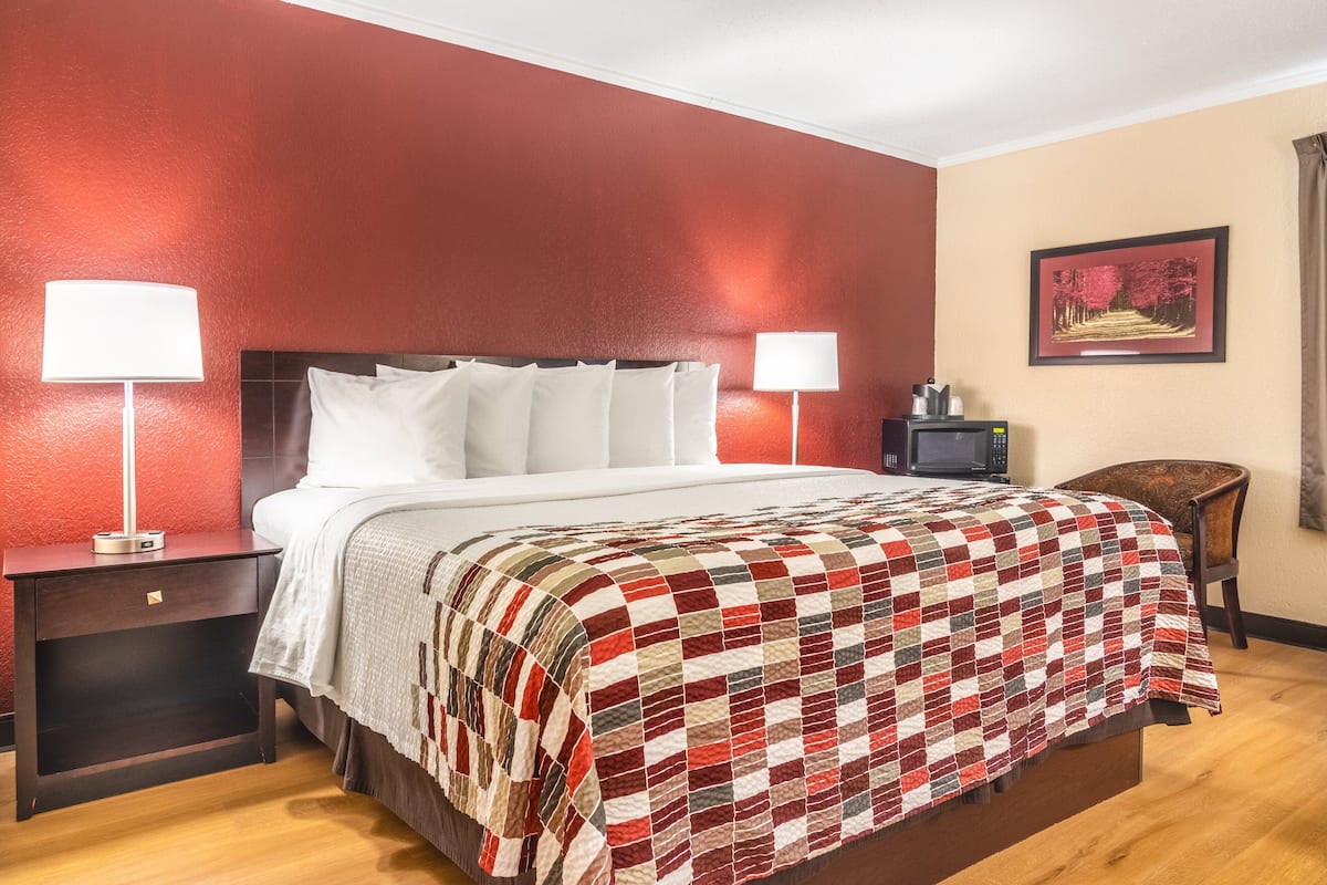 A hotel room with a large bed, two bedside lamps, a nightstand, a TV, and a framed picture on the wall.