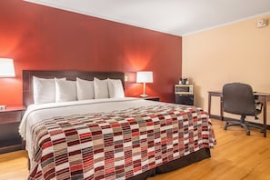 A hotel room with a large bed, a desk, and a chair.