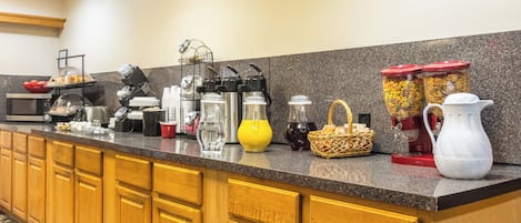 Una cocina de hotel con encimera de granito, armarios de madera y diversos electrodomésticos.
