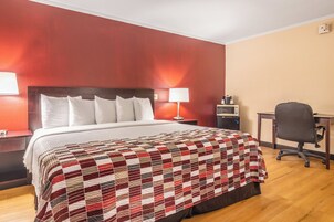 Una habitación de hotel con una cama grande, un escritorio, una silla y una mesita de noche.