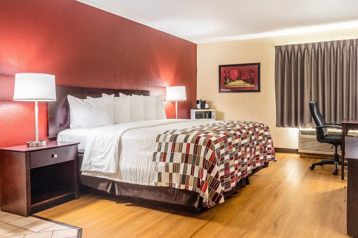 A hotel room with a large bed, two bedside tables with lamps, a desk, and a chair.