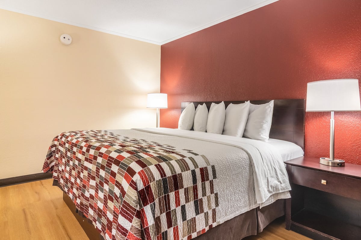 A hotel room with a bed, a nightstand with a lamp, and a wall with a textured finish.
