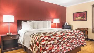A hotel room with a bed, two bedside lamps, a nightstand, a television, a chair, and a framed picture on the wall.