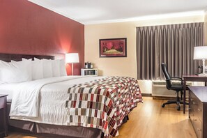 A hotel room with a large bed, a desk, a chair, a picture on the wall, and a window with curtains. - Red Roof Inn Ashtabula - Austinburg (Austinburg)
