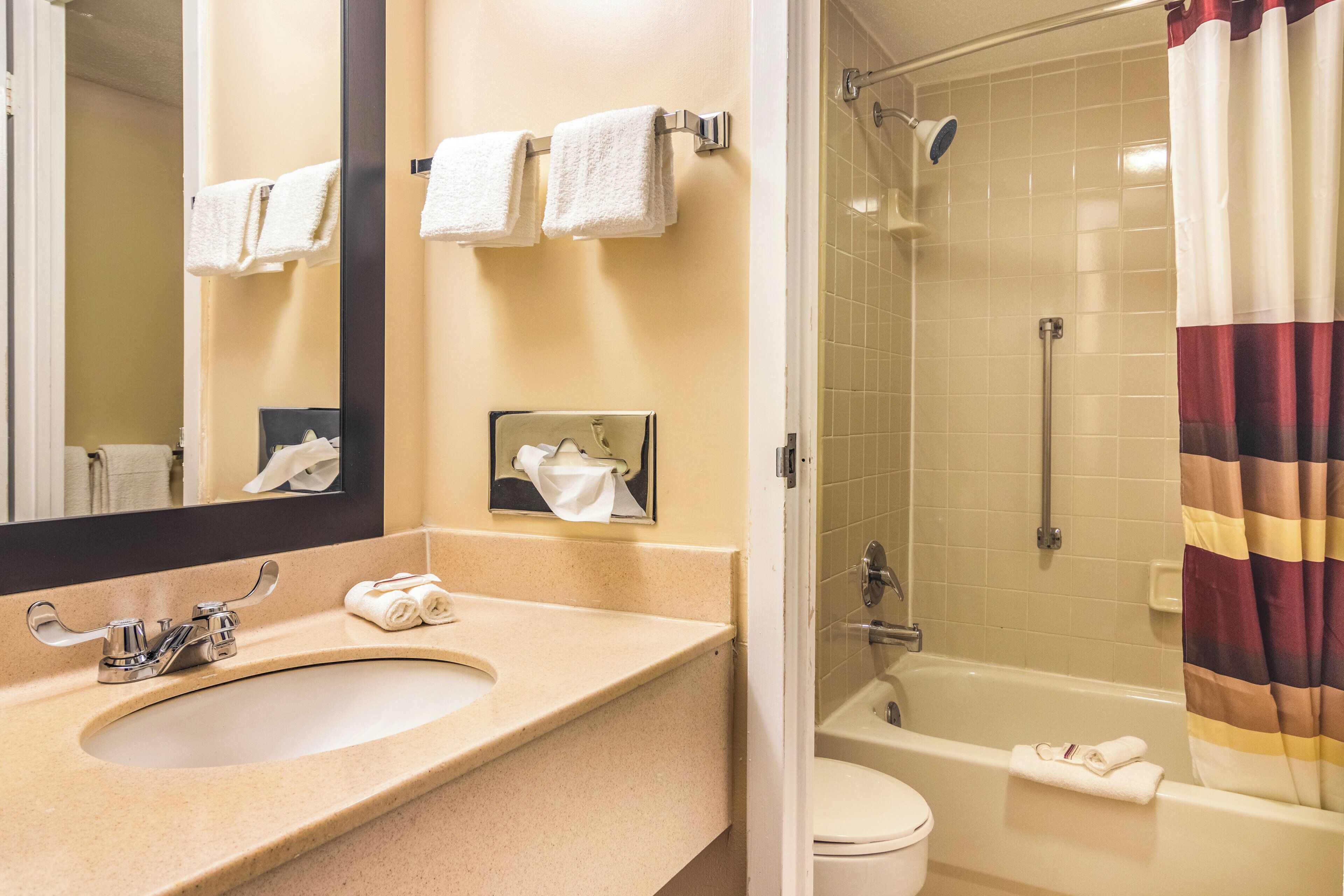 A bathroom with a sink, mirror, towel rack, and a shower with a curtain.