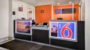 A hotel reception area with a modern design, featuring a reception desk, digital screens, and a large '6' sign.