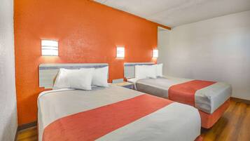 Een hotelkamer met twee bedden, oranje wanden en een houten vloer.