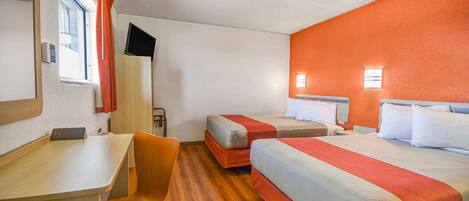 Habitación de hotel con dos camas, un escritorio, una silla y un televisor montado en la pared.