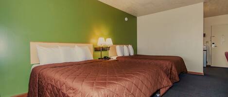 A hotel room with a large bed, a desk with a lamp, and a chair.
