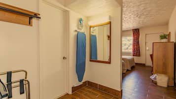 Un corridoio con pavimento in legno, una porta, uno specchio e un letto sullo sfondo.