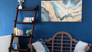 Una panca di legno con cuscini, una libreria a scala in legno e un quadro appeso al muro.