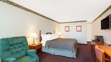 Una habitación de hotel con una cama, un escritorio, un televisor, una silla y dos lámparas.