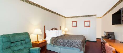 A hotel room with a bed, a desk, a television, a chair, and two lamps.